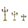 Mismatched vintage brass 5-prong candelabras with varied heights, warm patina finish, styled for wedding tablescape