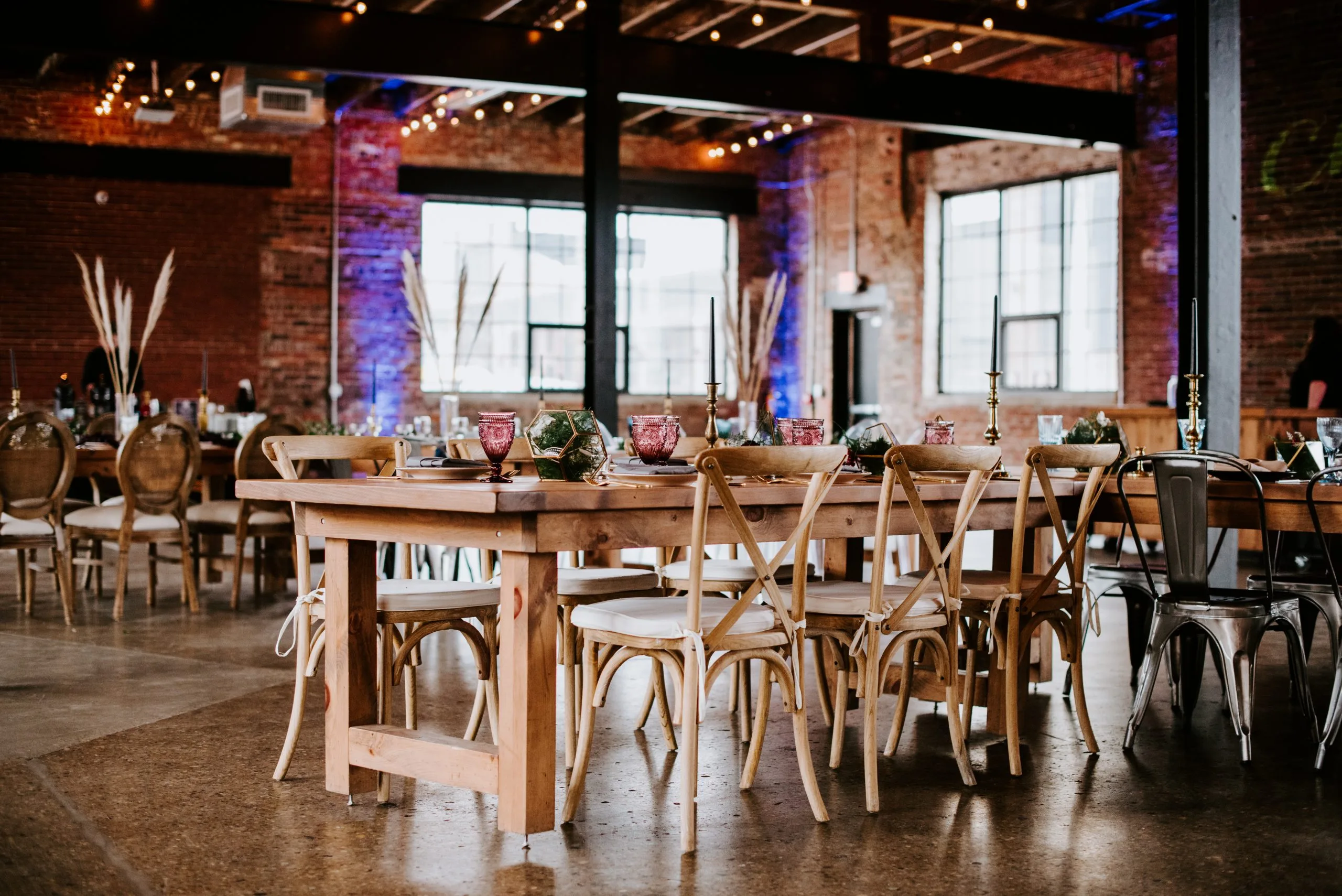 Crossback-Chairs-at-reception-scaled-1.jpg WEBP Wedding reception with farm table, cross back chairs, and table setting in an industrial venue.