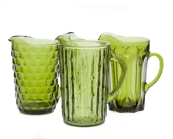 Vintage Olive Pitchers — mismatched olive green glass pitchers in varying shapes and heights, grouped on tabletop