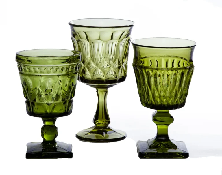 Three olive green mismatched glass goblets in different vintage patterns and stem shapes on a white background