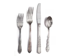 Vintage Silver Flatware — mismatched silver-toned vintage forks, knives, and spoons arranged on linen surface