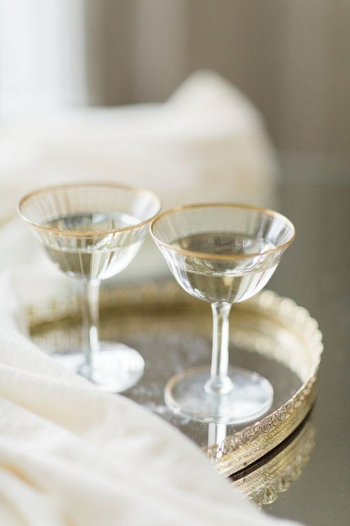 Two vintage glass coupes with gold rims on a mirrored gold tray