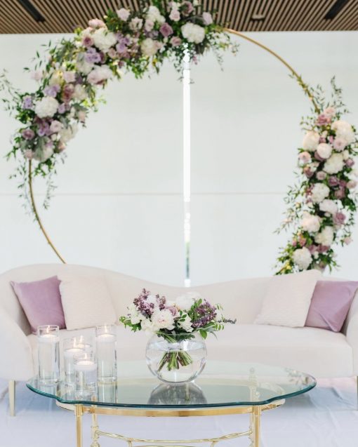 White curvy sofa with a glass top coffee table and decor