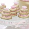 White porcelain pedestal cake stand with pink ribbon around the edge and sugar cookies on display