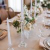 Glass candlesticks with white candles as part of an elegant tablescape with fine china