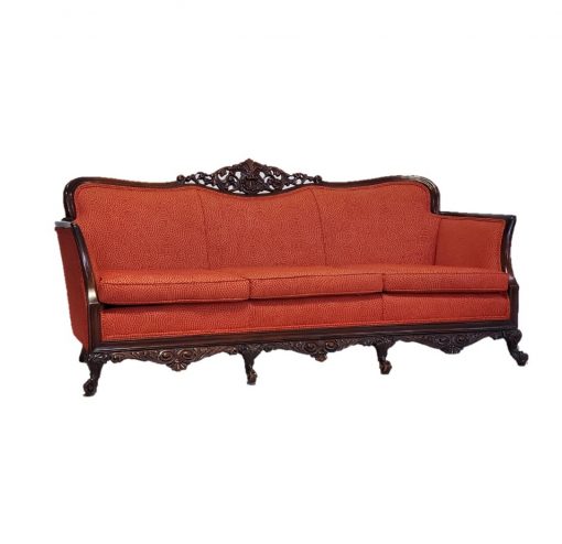 Orange/red vintage sofa with dark wood edges, feet, and top detailing. Side view