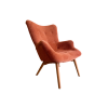 Wingback chair with flared arms in burnt orange. Wooden legs in neutral