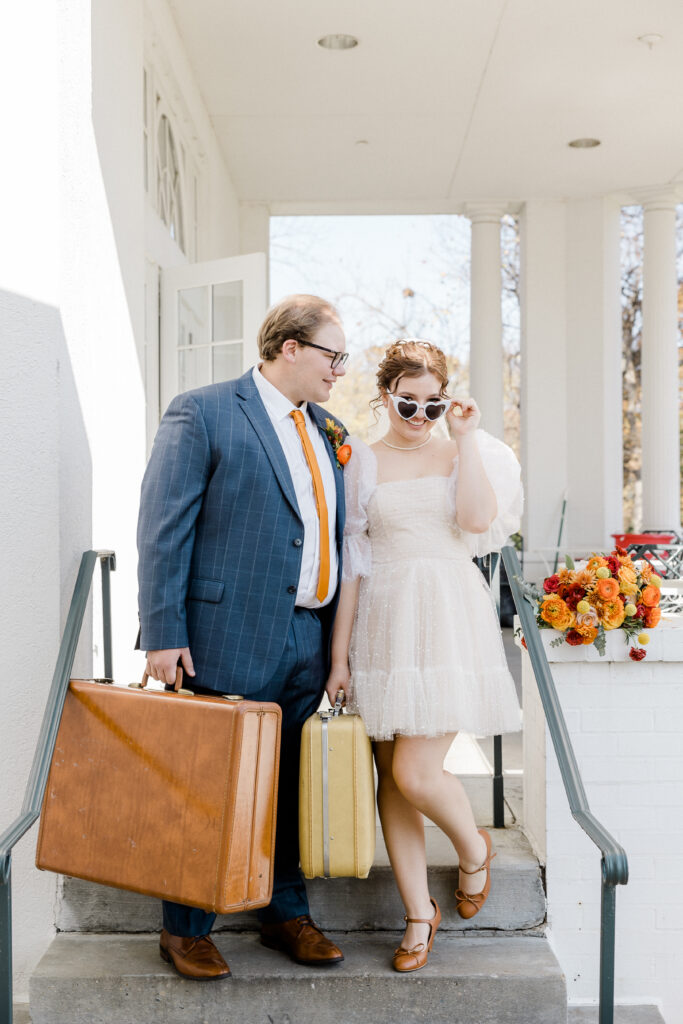 Couple with vintage suitcases standing on steps.