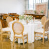 Round table with cream linen, chairs, and tablescape in an industrial venue