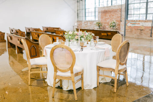 Round table with cream linen, chairs, and tablescape in an industrial venue