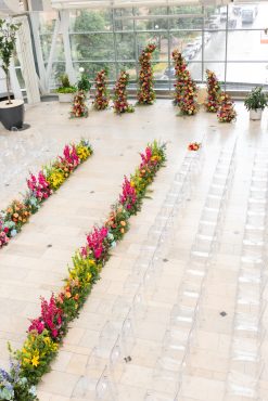 Runway aisle for wedding with ghost chairs in a large glass venue
