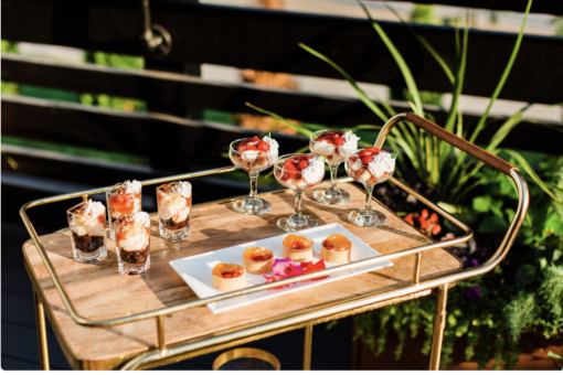 Alden bar cart with a wooden top and gold edging with delicious foods