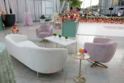 White velvet sofa, two dusty pink barrel swivel armchairs, gold accent side table.