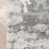 close up on corner of rug with patches of different shades of gray and white