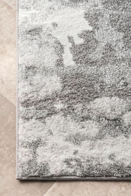 close up on corner of rug with patches of different shades of gray and white