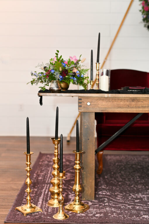 Extra large candlesticks on a rug on the floor in front of a sweetheart table