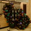 Black metal grid used to display seating chart at wedding reception. Balloon decor behind