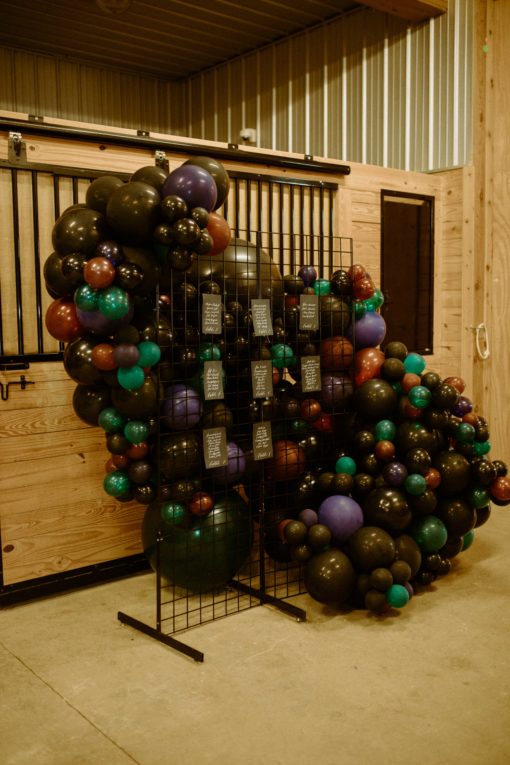 Black metal grid used to display seating chart at wedding reception. Balloon decor behind