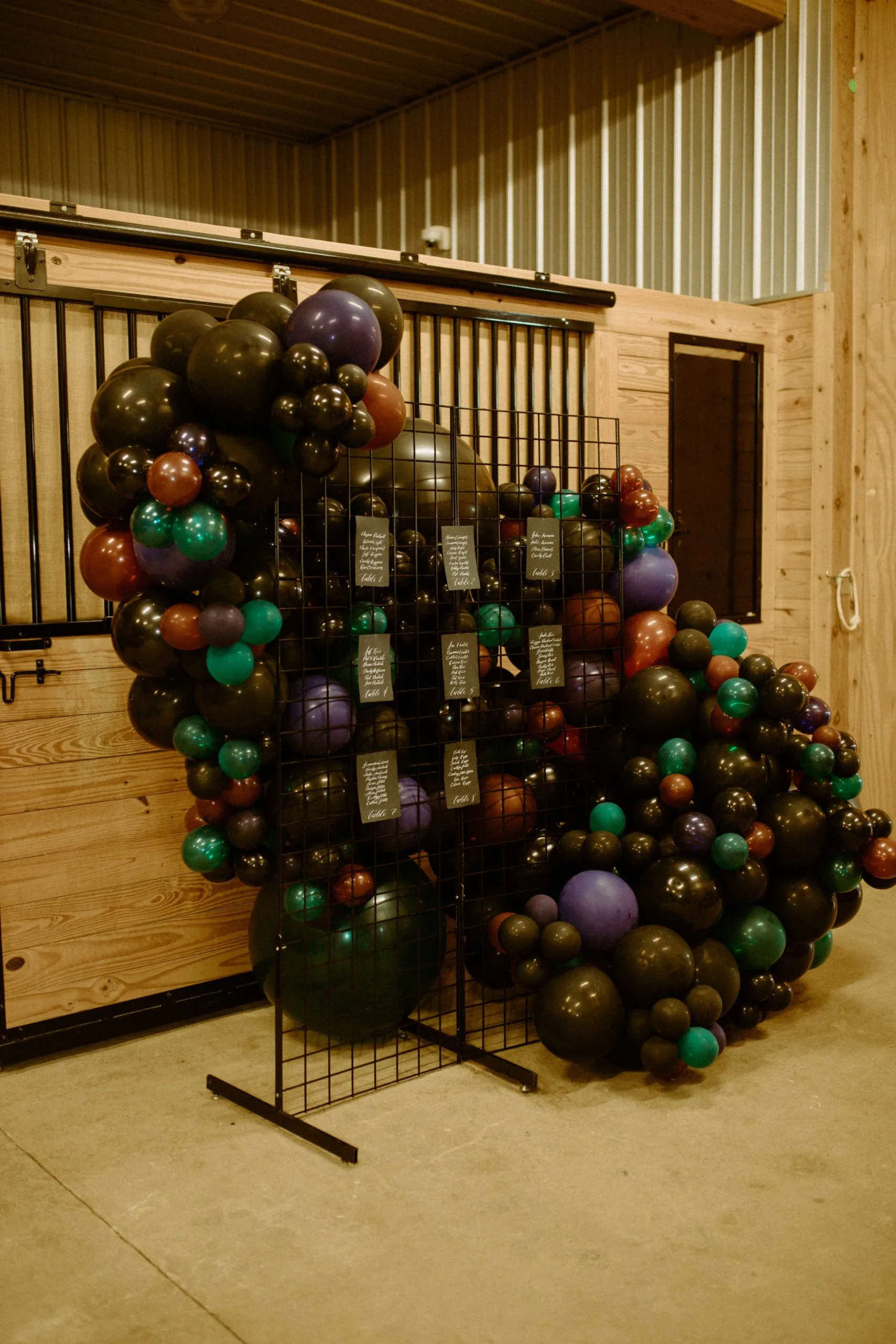 Black metal grid seating chart at wedding reception WEBP Black metal grid used to display seating chart at wedding reception. Balloon decor behind