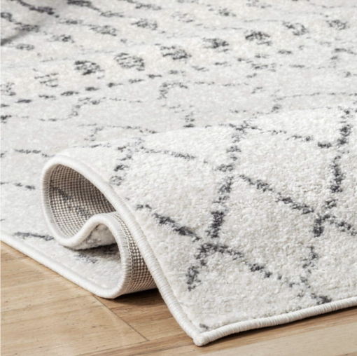 Folded corner of rug. white background with gray lines making diamonds