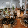 Dinner party tablescape with black plates, clear class candlesticks and brown mismatched goblets