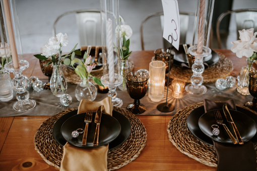 Dinner party tablescape with black plates, clear class candlesticks and brown mismatched goblets