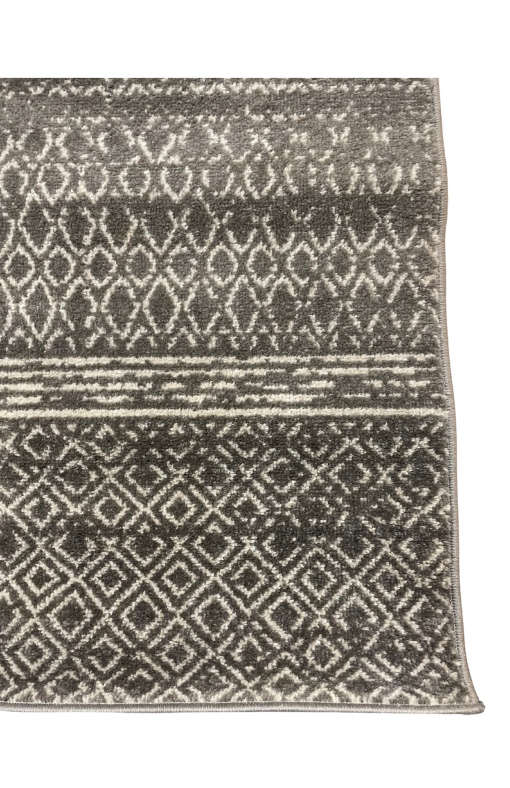 Close up of gray and white rug. Parallel lines, diamonds, and other geometric designs.