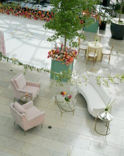 Velvet light pink arm chairs in soft seating lounge set up with gold side and coffee tables