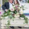 Close up on drawer on the cream coffee table. Florals draping over the side. Couple blurry in the background