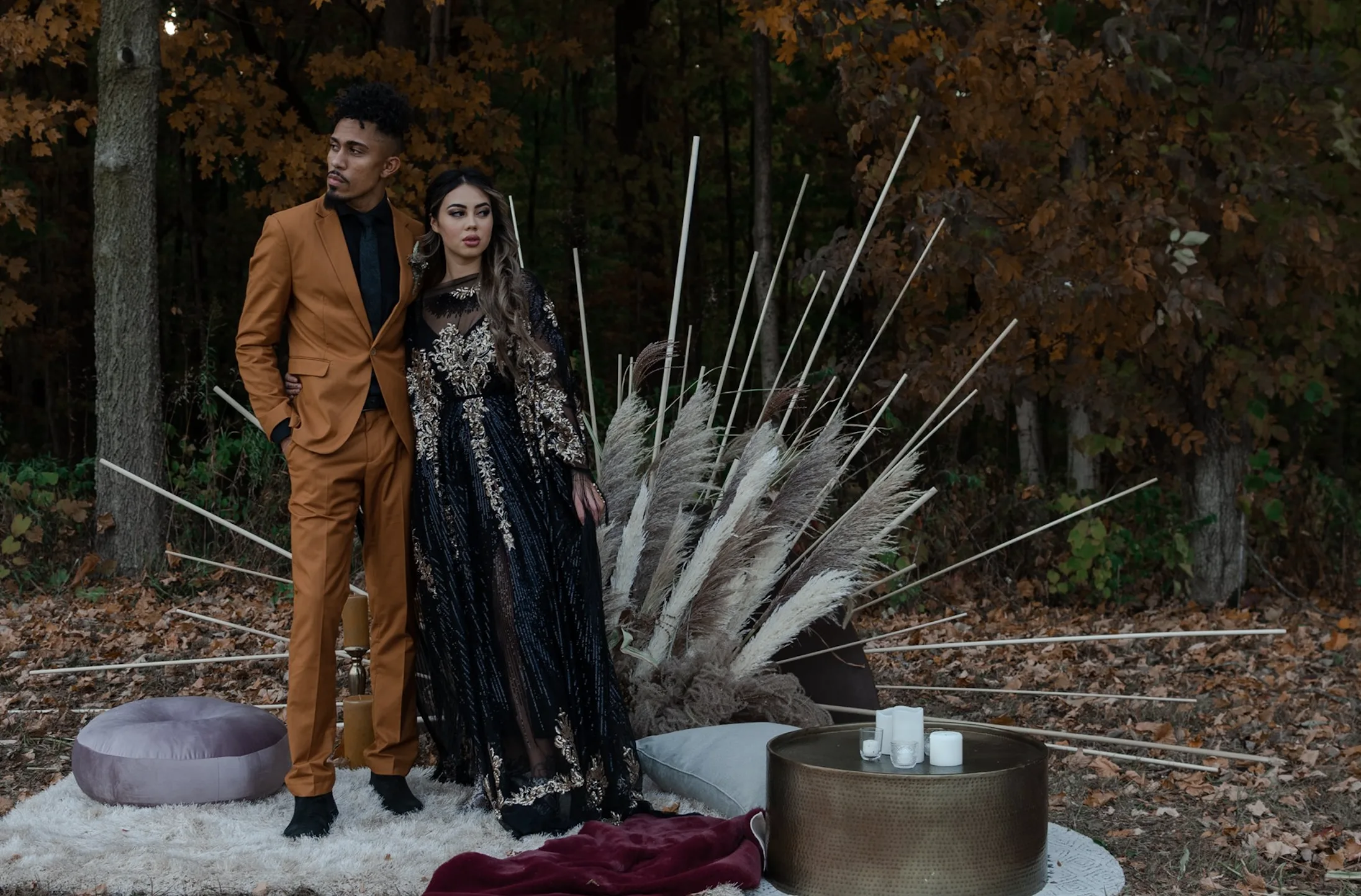 Couple in a moody shoto shoot WEBP Moody photoshoot with a diverse couple standing on rugs with a gold coffee table and a dramatic backdrop.