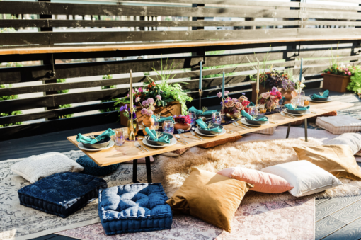 Colorful pillows and cushions on a variety of rugs around a low long table with beautiful tablescape