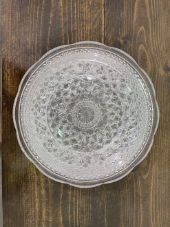 Set of cut glass salad and dinner plates on a dark wood table.