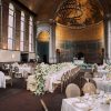 High end dining chairs with cushions in a wedding reception. One long table down the middle with round tables and square tables around.