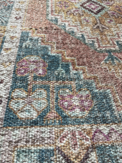 Close up of rug with turquoise background (in this location) and off white and pink details
