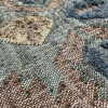 Close up of rug with brown and blue and green base with yellow diamond shape