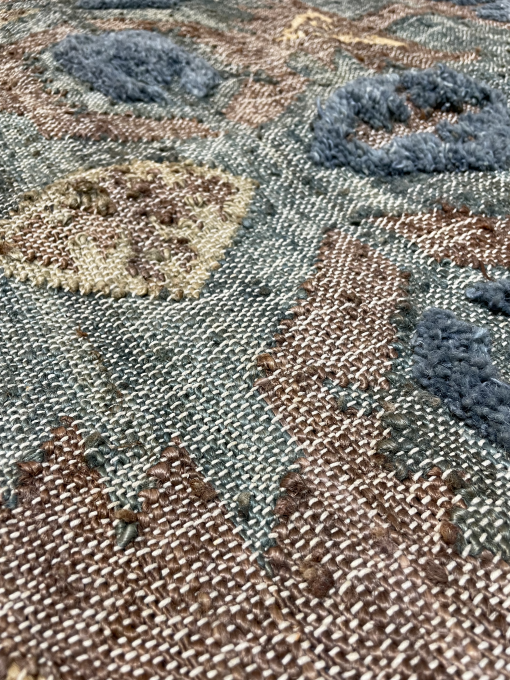 Close up of rug with brown and blue and green base with yellow diamond shape