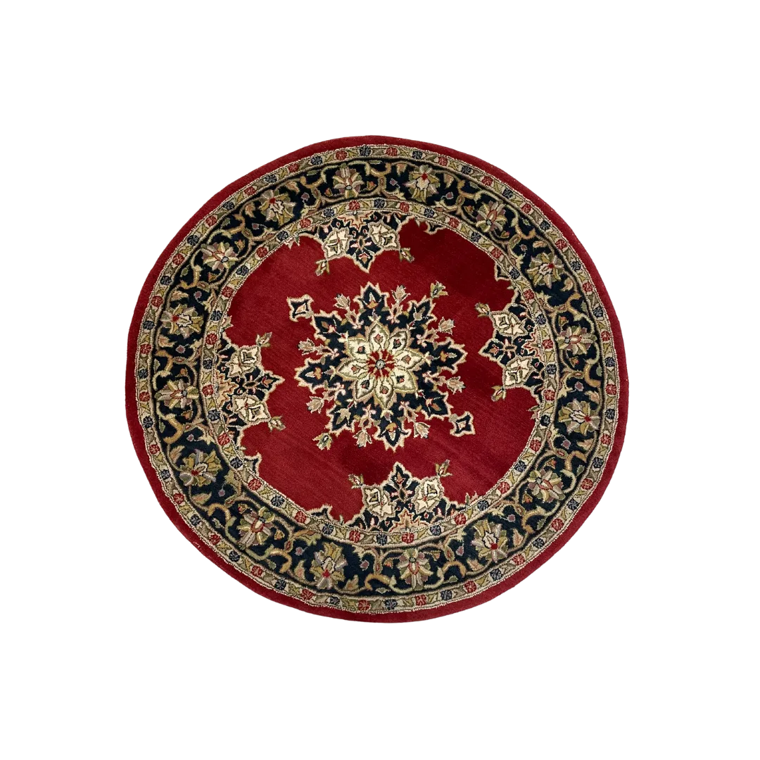 Huxton Round Rug WEBP Ariel view of a round rug with navy flowered border and deep red inside. Navy and white medallion in the center.