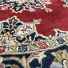 Close up of rug: navy and deep red background with lighter blue, green, cream ornate designs