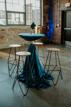 Four stools around a cocktail table draped in blue linen with florals on top