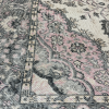 Detail on the border edge of the rug. Black Edging with pink, gray, and cream paisley designs