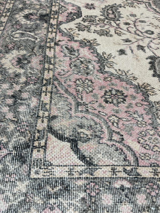 Detail on the border edge of the rug. Black Edging with pink, gray, and cream paisley designs