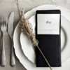 White porcelain dinner and salad plates with a napkin and silverware at a table setting