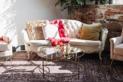 Elegant birthday party lounge rental in a downtown Indianapolis venue featuring a vintage velvet sofa, a modern gold coffee table, and exposed brick walls.
