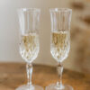 Two ornate champagne flutes with wine, sitting on a dark wood table