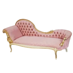 Side view of a pink chaise lounge with the left side set up for resting - higher arm and back. Cream and gold detailing on wood edges around the back and legs.