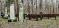 Freestanding doors and stained glass create the entrance to this outdoor wedding ceremony with church pews. Surrounded by woods
