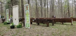 Freestanding doors and stained glass create the entrance to this outdoor wedding ceremony with church pews. Surrounded by woods