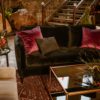 Black sofa with gray barrel armchair and black glass coffee table. Decorated with flowers. Boho lounge area at an event.