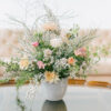 Glass topped coffee table with wooden scalloped edges with florals. Pink sofa in background