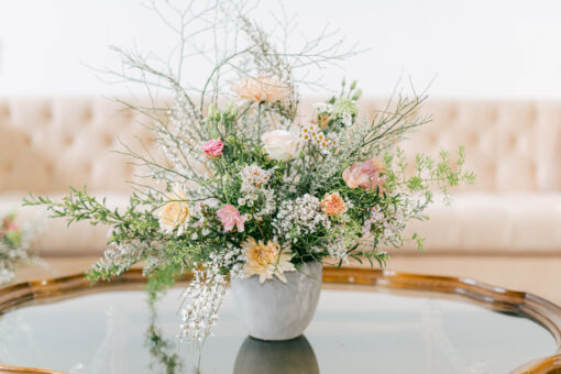 Glass topped coffee table with wooden scalloped edges with florals. Pink sofa in background